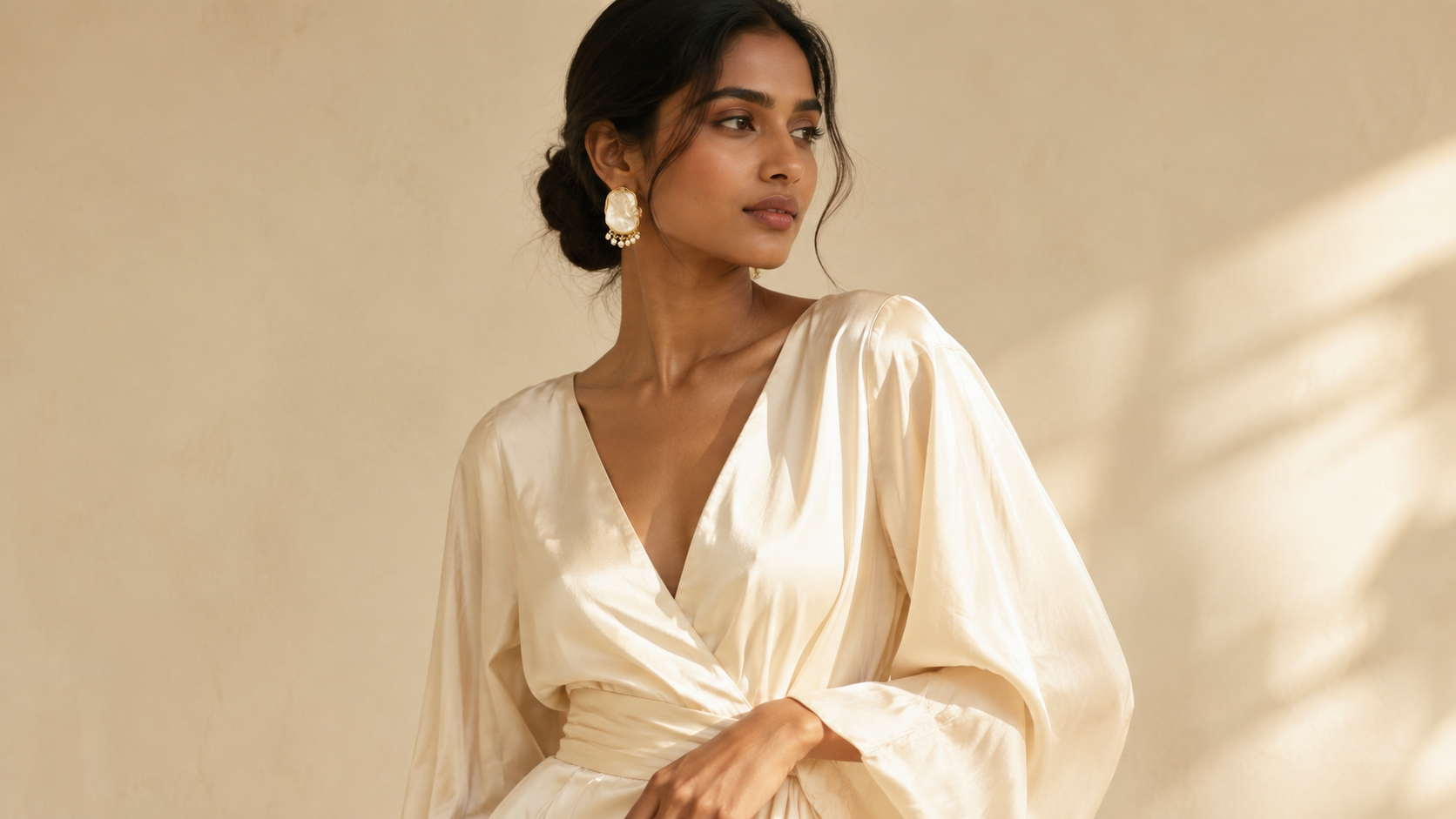 Model wearing mother-of-pearl drop earring, cream silk outfit